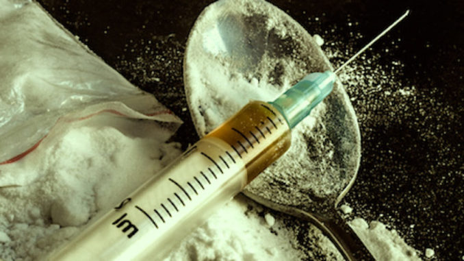 Drug syringe and cooked heroin on spoon